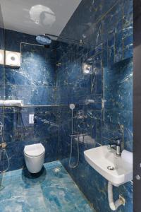 a blue tiled bathroom with a toilet and a sink at TheSunlitHaven Pool GlassRooms Lawn in Raigīr