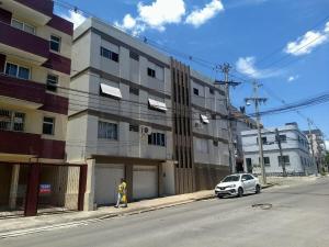 a white car parked on a street next to a building at 101- Apartamento 2 quartos próximo UFN, com vaga de garagem in Santa Maria