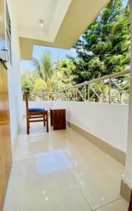 a room with a chair and a balcony with trees at JM Suites Prasanti Hotel in Helāpākari