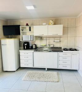 a white kitchen with a sink and a refrigerator at Casa de família na Serra Gaúcha in Bento Gonçalves