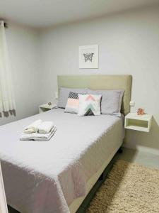 a bedroom with a bed with white sheets and pillows at Casa de família na Serra Gaúcha in Bento Gonçalves