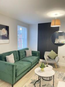 a living room with a green couch and a table at Brand New City Centre Apartment - Free offsite Parking Available in Nottingham