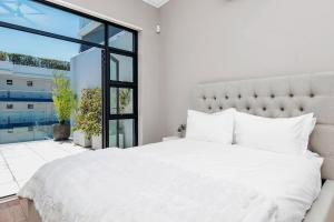 a bedroom with a white bed and a large window at Sea Point Luxury Escape with Private Pool in Cape Town +50 photos