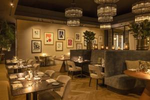 a restaurant with tables and chairs and chandeliers at Dukes' Palace Brugge - by Dukes' Hotel Collection in Bruges