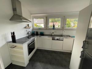 a kitchen with white cabinets and a sink and two windows at Ferienwohnung Heilsberg in Gottmadingen +3 photos