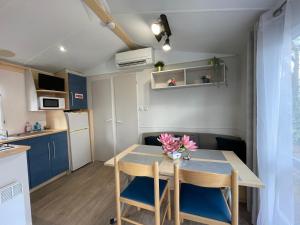 a small kitchen and dining room with a table and chairs at MH-MAUFAY -- Mobil'home au Coeur de la Vendée in La Boissière-de-Montaigu +19 photos