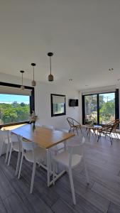 a dining room with a table and chairs and windows at Maresia Dos habitaciones, dos baño y Calefacción losa radiante in Quequén