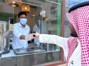 a person holding up a cell phone in front of a man at فندق ربوة الصفوة الذهبي Rabwat Al Safwah Golden Hotel in Al Madinah