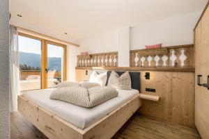 a bedroom with a large bed with a large window at Forchnerhof Nature & Mountain View Apartments in Terento