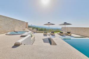 a swimming pool with chairs and umbrellas on a building at Aegean Sunset Villas & Spa 'Villa Sun' in Skouloúfia