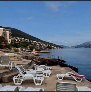 a group of white chairs and tables on the water at Simphony Apartments in Tivat