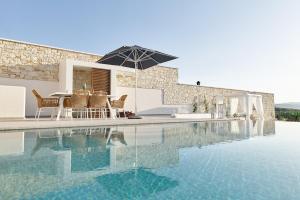 a swimming pool with a table and an umbrella at Aegean Sunset Villas & Spa 'Villa Sky' in Skouloúfia