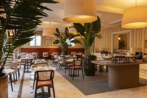 a restaurant with tables and chairs and potted plants at Dukes' Palace Residence - by Dukes' Hotel Collection in Bruges