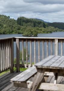 een houten bank op een terras met uitzicht op een meer bij New Brachkashie Cottage in Whitebridge