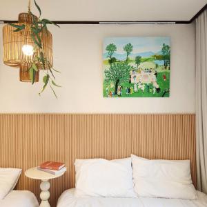 a bedroom with a painting above a bed and a table at Sosodam Stay in Seoul