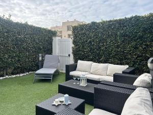 Un patio con un sofá y mesas y un seto. en Alloggio Soldatelli, en Fregene