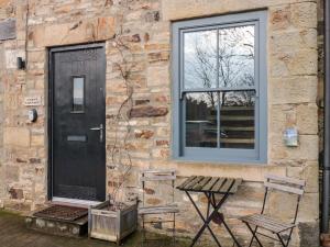 a brick house with a black door and a window at Cedar Cottage in Barnard Castle