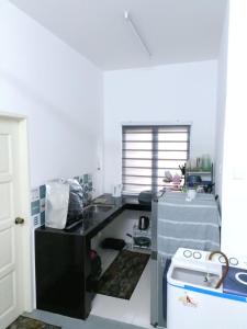 a kitchen with a black counter and a sink at Senja Kelabu Homestay in Kampong Bukit Tok Beng +3 photos