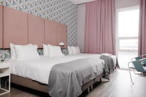2 letti in una camera d'albergo con pareti rosa di ODDSSON Midtown Hotel a Reykjavik