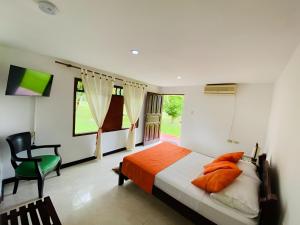 a bedroom with a bed and a chair and window at Finca Campestre la carolina in Villavicencio