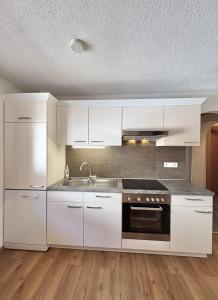 a kitchen with white cabinets and a sink at Haus Sonnberg in Kappl