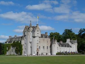 a castle with a flag on top of it at Swiss Cottage in Ballindalloch