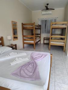 a bedroom with a bed with a purple blanket on it at Colônia de Férias Beleza e Arte in Caraguatatuba