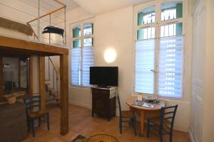 Habitación con mesa, TV y algunas ventanas. en Les Halles superbe studio 4 personnes Wi-Fi Climatisation Netflix cœur de ville et historique, en Béziers