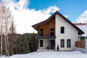 a house in the snow with trees in the background at Cabana Orcas in Harghita-Băi