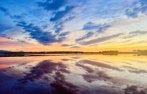 a reflection of the sky in the water at sunset at Villa Vista Mar La Marina Piscine privée in Elche