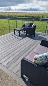 a deck with two chairs and a table and benches at Shanadune in Tralee