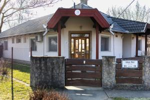 a white house with a wooden fence in front of it at Tükör apartman Martonvásár in Martonvásár