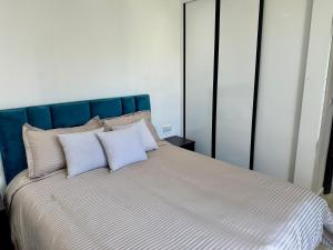 un letto con testiera blu e tre cuscini di La perle de Taghazout Bay a Taghazout Altre 17 foto