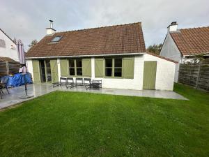 un cortile con una casa con prato e panchine di Huisje aan de zee Duinendaele a De Panne