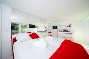 een witte slaapkamer met rode en witte kussens op een bed bij Favorite Stays - Suite and More - Deluxe in Neuss