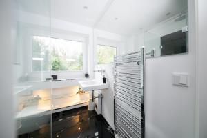 een witte badkamer met een wastafel en een raam bij Favorite Stays - Suite and More - Deluxe in Neuss +61 foto's