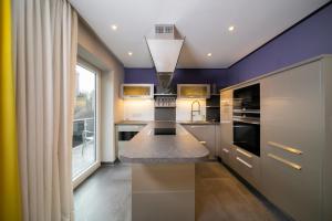 een keuken met paarse muren en een groot raam bij Favorite Stays - Suite and More - Deluxe in Neuss