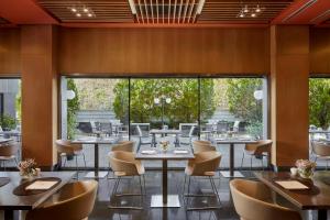 un restaurante con mesas, sillas y ventanas grandes en NH Madrid Las Tablas, en Madrid 37 fotos más