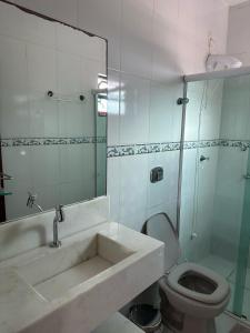 a bathroom with a sink and a toilet and a mirror at Apartamento no centro de Garopaba bem próximo a praia in Garopaba