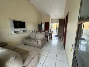a living room with a couch and a tv at Apartamento no centro de Garopaba bem próximo a praia in Garopaba
