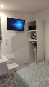 a bedroom with a bed and a tv on the wall at Promotion du Jour - Studio Le Palmier in Deuil-la-Barre +10 photos