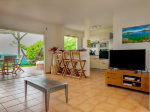 a living room with a flat screen tv and a kitchen at villa Caraibes proche plage in Sainte-Anne