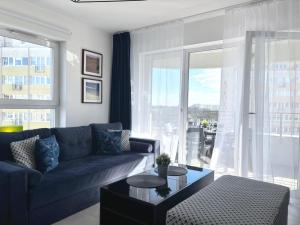 ein Wohnzimmer mit einer blauen Couch und einem großen Fenster in der Unterkunft Sun Towers - Apartamenty Bryza - Apartamenty z parkingiem in Świnoujście