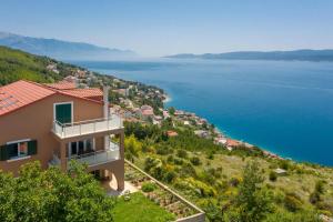 a house on a hill next to the water at Apartmani Noah - Mia in Celina