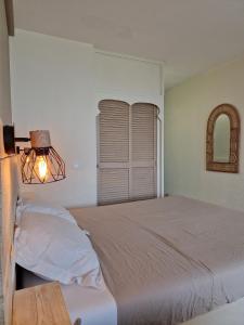 a bedroom with a bed with a lamp and a window at Ti Dyaman - Studio vue mer & accès piscine gratuit in Le Diamant