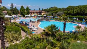 basen w ośrodku z palmami i parasolami w obiekcie Hotel Bella Italia w mieście Peschiera del Garda