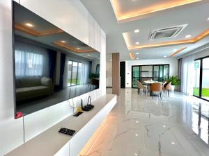 Una sala de estar con un televisor grande en la pared. en 芭堤雅ins风独栋泳池别墅, en Nong Prue