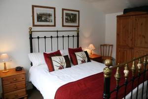 a bedroom with a bed with red and white pillows at Awd Tuts 17th Century Cottage by the harbour in Whitby