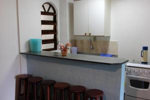 uma cozinha com um balcão com uma fila de bancos em Farol das Gaivotas Pousada e Residence em Caraguatatuba