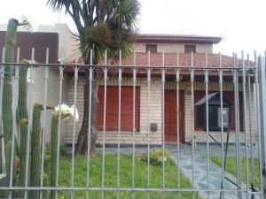 a fence in front of a house with a palm tree at Casa chalet neco in Necochea